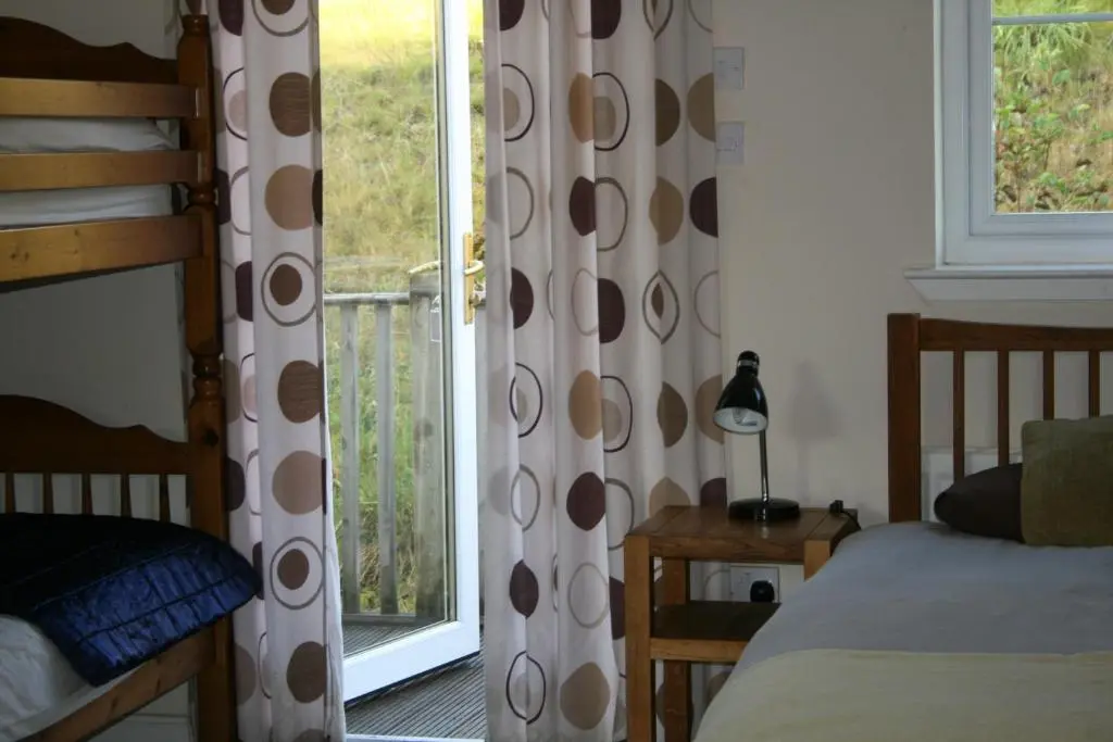 a bedroom with a bed and a sliding glass door at BCC Loch Ness Hostel in Bearnock