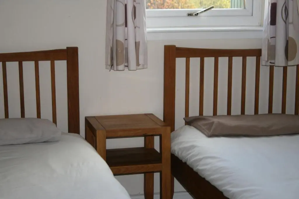 two beds in a room with a window and a table at BCC Loch Ness Hostel in Bearnock