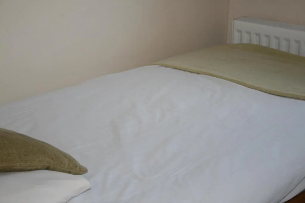 a white bed with a blanket on top of it at BCC Loch Ness Hostel in Bearnock
