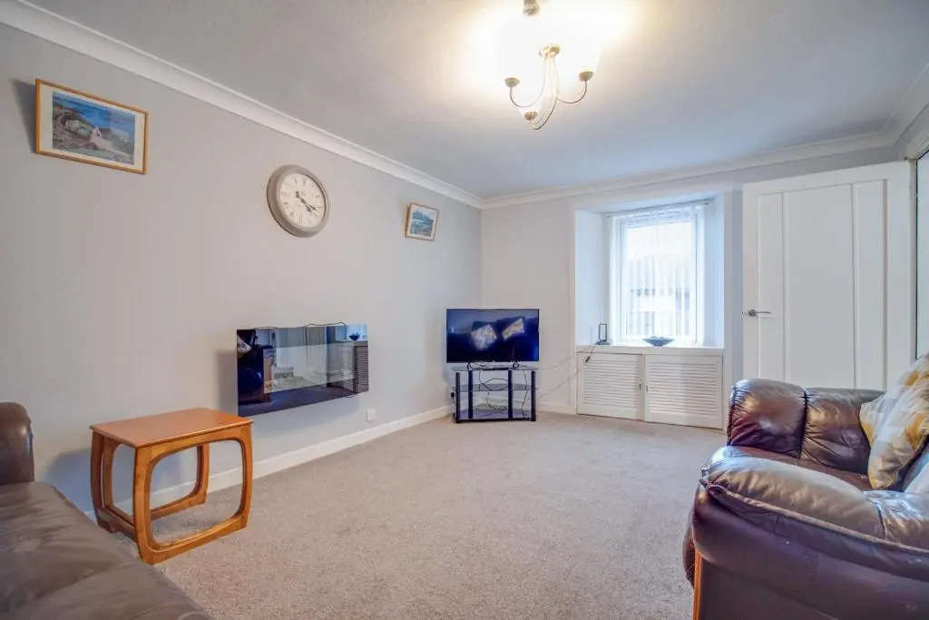 a living room with a couch and a clock on the wall at Novar 4 Bedroom House Alness in Inverness