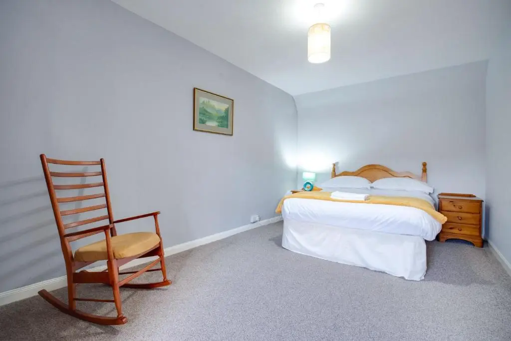 a bedroom with a bed and a wooden chair at Novar 4 Bedroom House Alness in Inverness
