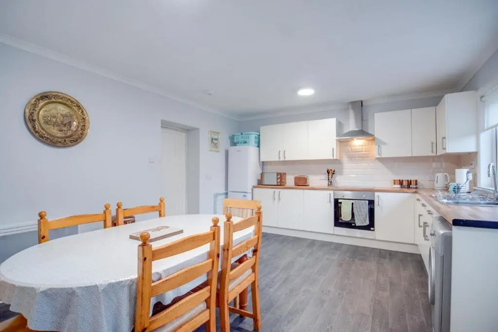 a kitchen with a table and chairs in a room at Novar 4 Bedroom House Alness in Inverness