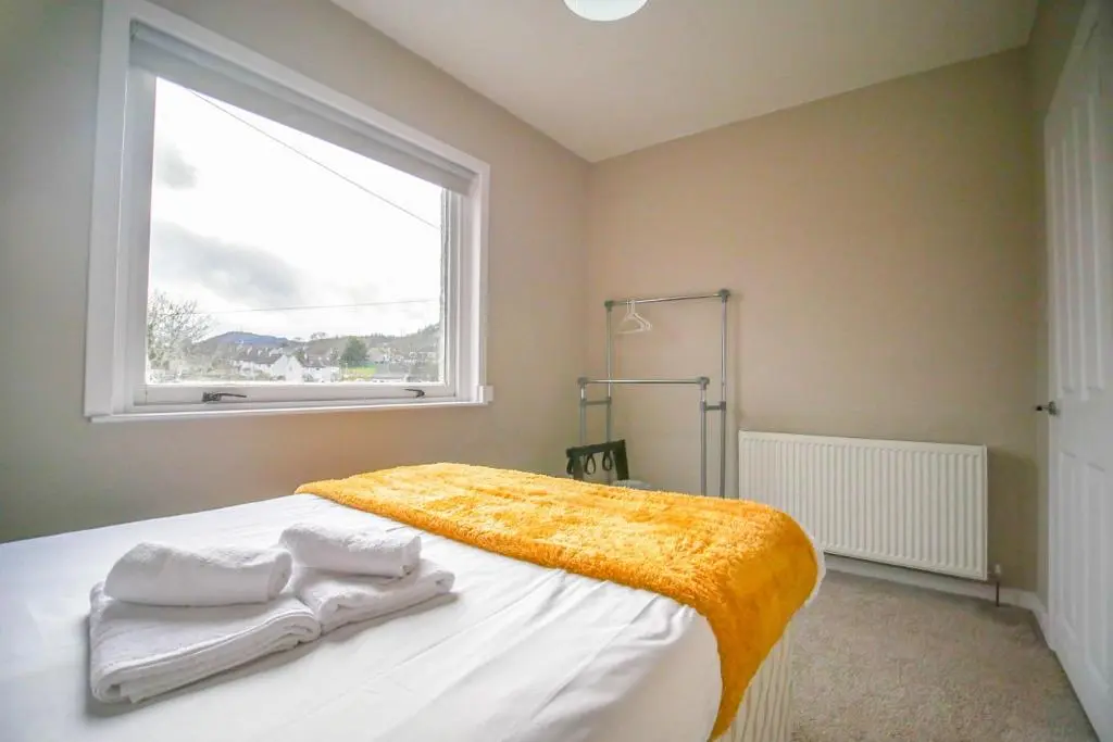 a bedroom with a bed with a yellow blanket and a window at Telford St 4 Bedroom House Inverness in Inverness