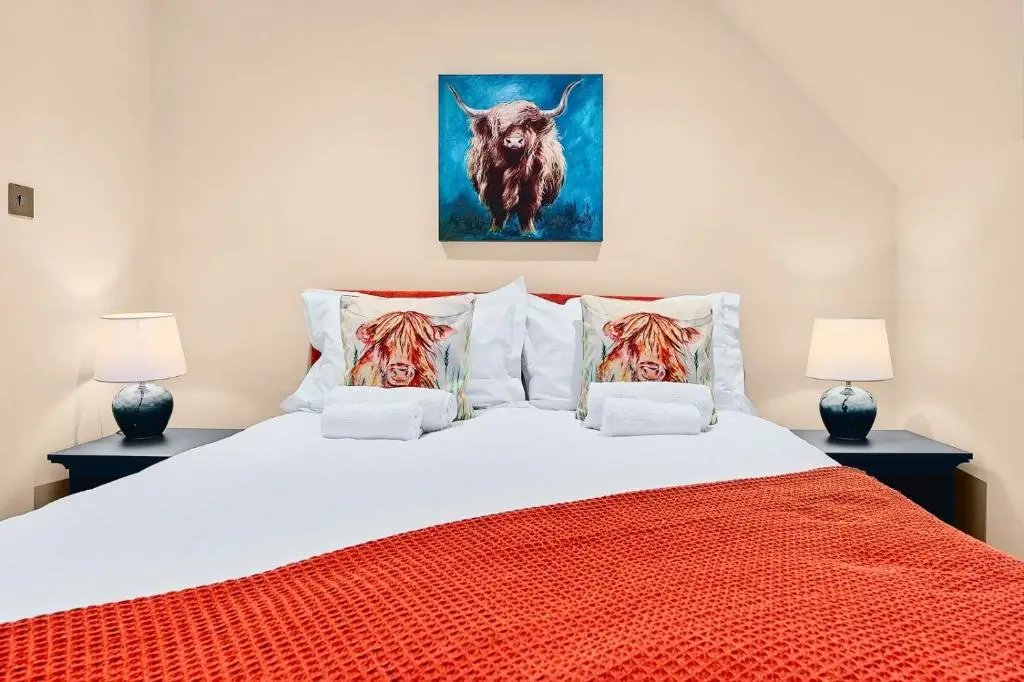 a bedroom with a large bed with an orange blanket at Kinkell House Rooms in Cononbridge