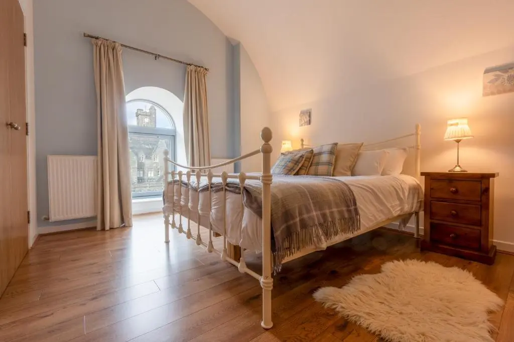 a bedroom with a bed and a large window at Abbey Church Upper North Aisle Luxury Self Catering 2 bedroom Apartments in Fort Augustus