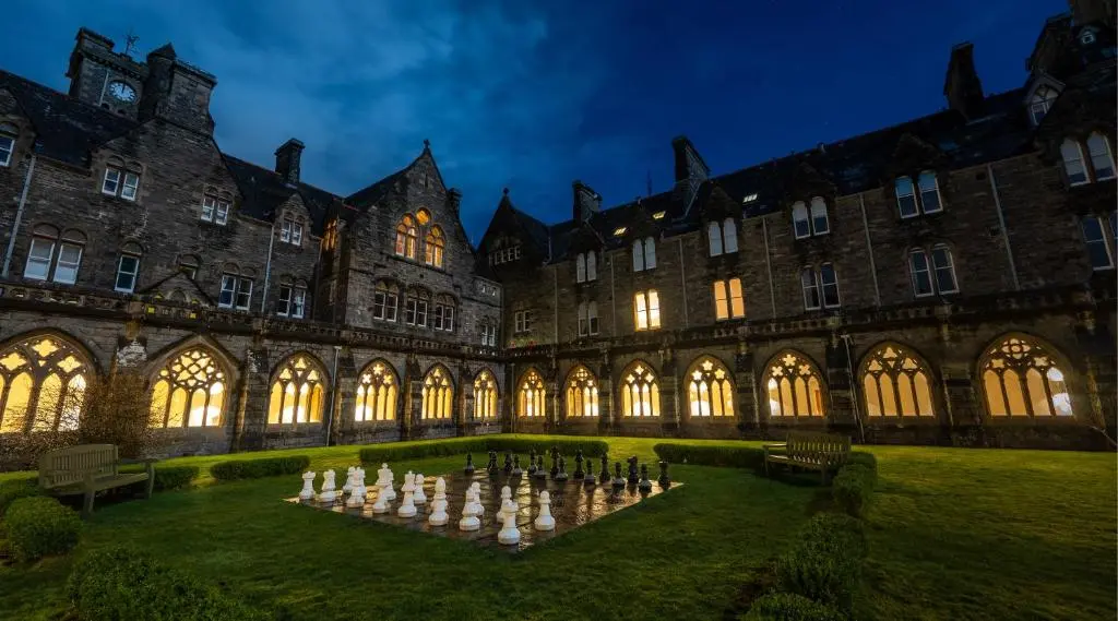 a large building with a group of people in a courtyard at Abbey Church Upper North Aisle Luxury Self Catering 2 bedroom Apartments in Fort Augustus