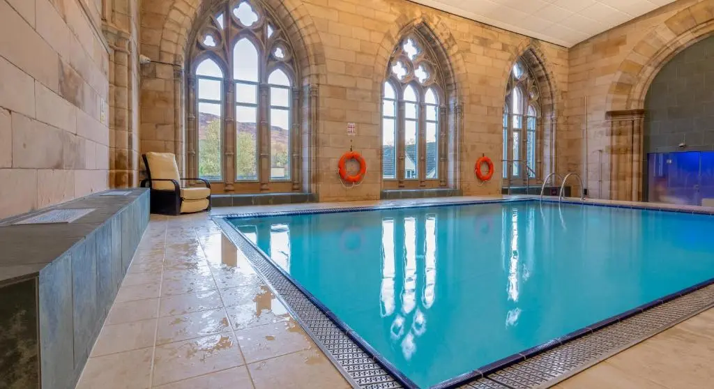 a large swimming pool in a building with windows at Abbey Church Upper North Aisle Luxury Self Catering 2 bedroom Apartments in Fort Augustus