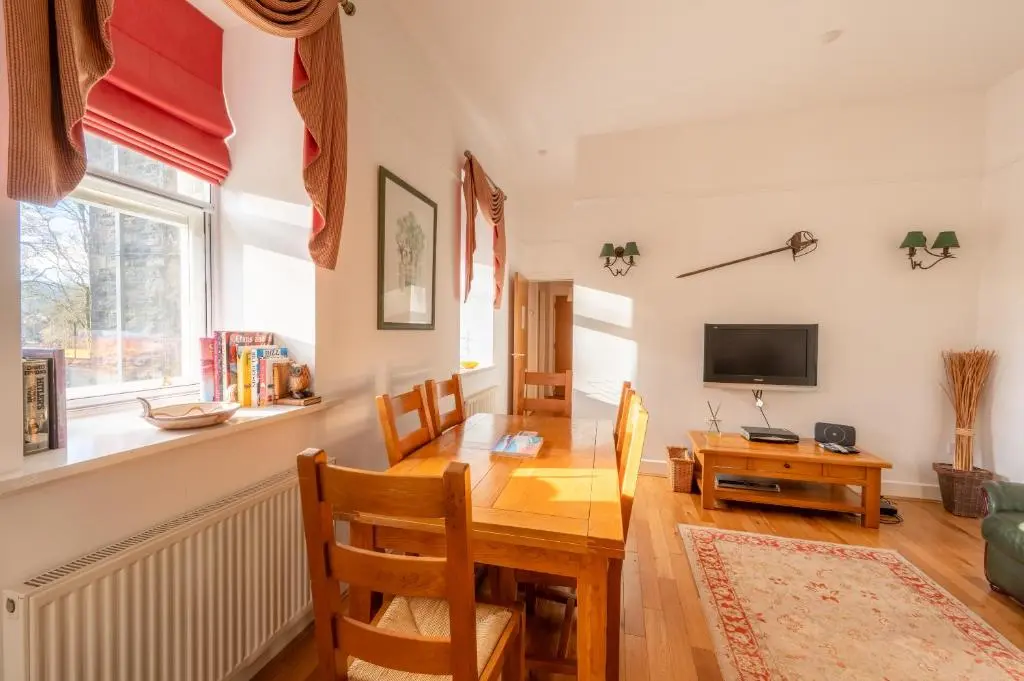 a dining room with a table and a television at Major's Apartment 3 Bedroom Self Catering Property in historic Abbey in Fort Augustus