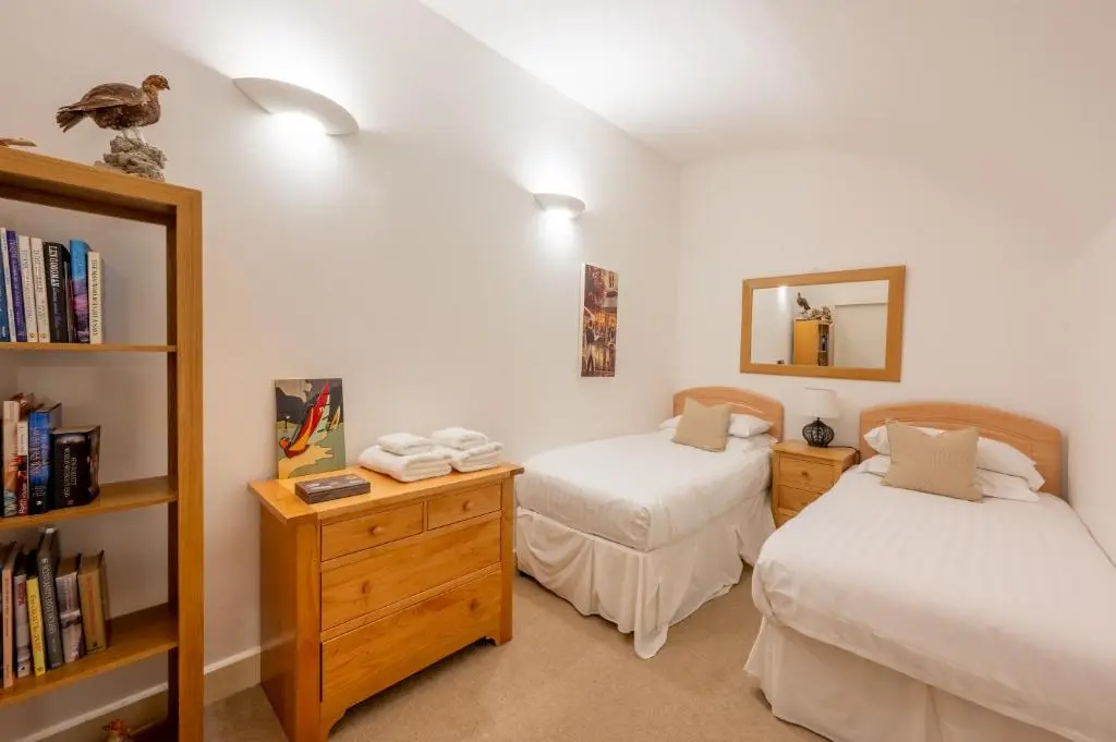 a bedroom with two beds and a book shelf at Major's Apartment 3 Bedroom Self Catering Property in historic Abbey in Fort Augustus