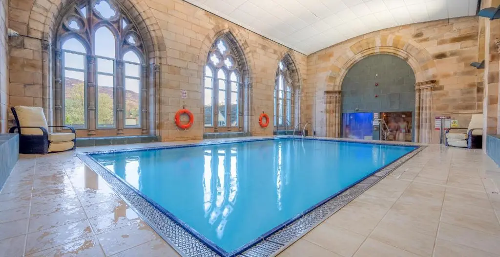 a large swimming pool with blue water in a building at Major's Apartment 3 Bedroom Self Catering Property in historic Abbey in Fort Augustus