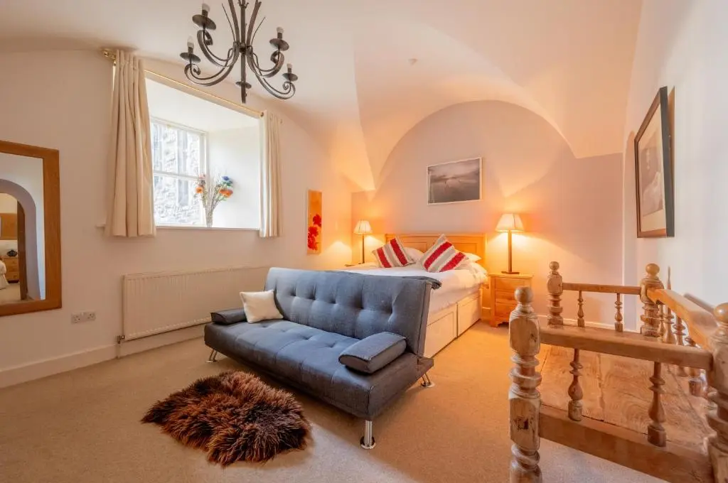 a bedroom with a bed and a blue couch at Major's Apartment 3 Bedroom Self Catering Property in historic Abbey in Fort Augustus