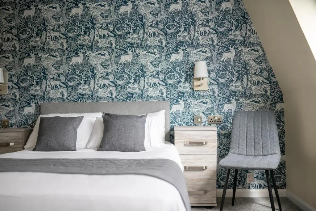 a bedroom with a bed and a blue and white wallpaper at Loch Ness Drumnadrochit Hotel in Drumnadrochit