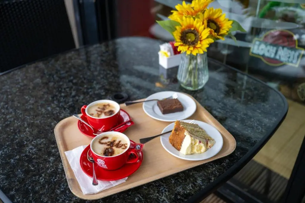 a table with two cups of coffee and a piece of cake at Loch Ness Drumnadrochit Hotel in Drumnadrochit