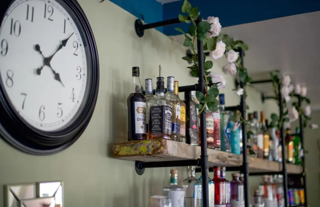 a clock hanging on a wall next to bottles of alcohol at Loch Ness Drumnadrochit Hotel in Drumnadrochit