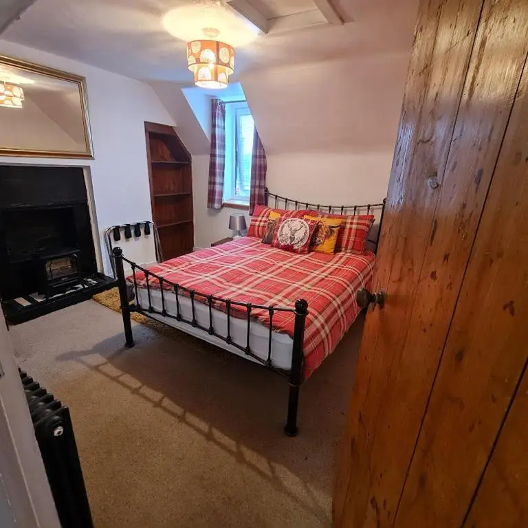 a bedroom with a bed in a room with a fireplace at Ness City Cottage - Attic Apartment in Inverness