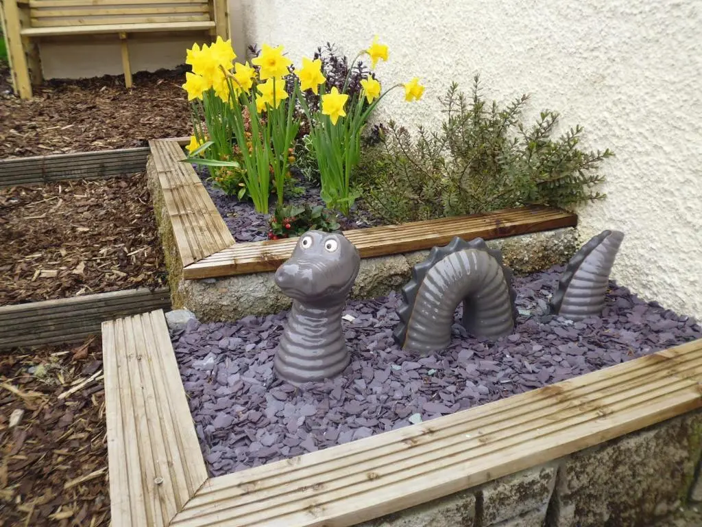 a garden with a lizard and a bench and flowers at Foyers House in Foyers