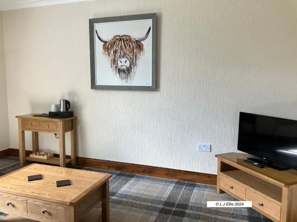 a living room with a picture of a bull on the wall at Foyers House in Foyers