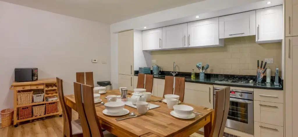 a kitchen with a wooden table with white appliances at Abbey Holidays Loch Ness Luxury Self Catering 2 Bedroom Cottages in Fort Augustus