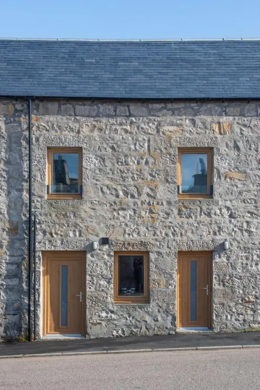 a stone building with four doors and windows at Apartment Harbour Nights Deluxe 7C by Interhome in Lossiemouth