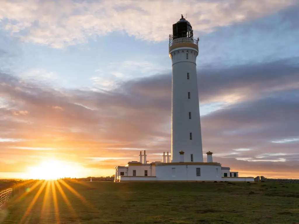 a lighthouse on a field with the sunset in the background at Apartment Harbour Nights Deluxe 7B by Interhome in Lossiemouth