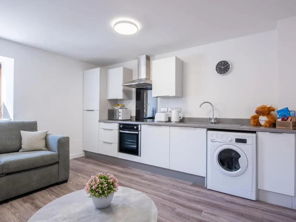 a kitchen with white cabinets and a couch and a table at Apartment Harbour Nights Deluxe 7B by Interhome in Lossiemouth