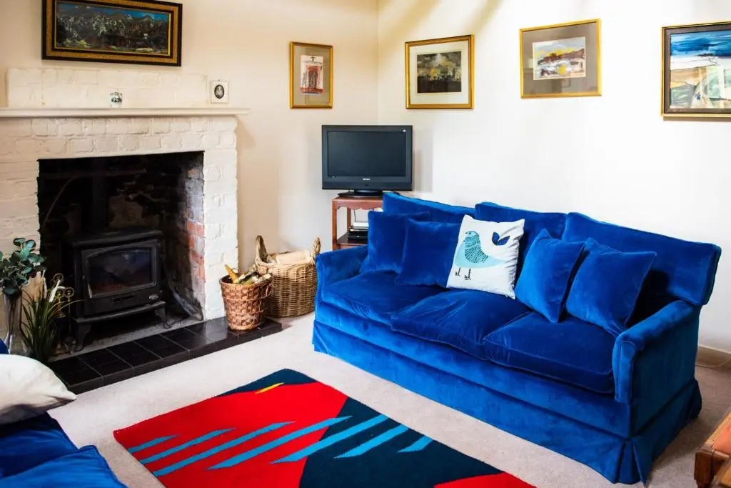 a living room with a blue couch and a fireplace at Colmeallie Bothy - Seasgair Lodges in Brechin