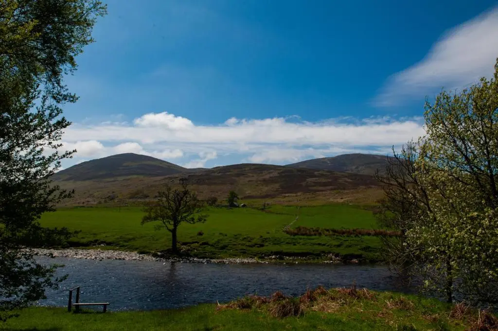 a lake in a field with mountains in the background at Colmeallie Bothy - Seasgair Lodges in Brechin