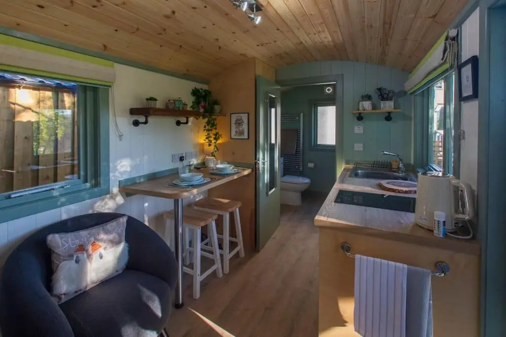 a small kitchen and living room in a tiny house at Cosy Shepherds Hut with hot tub in the Scottish Highlands in Stittenham