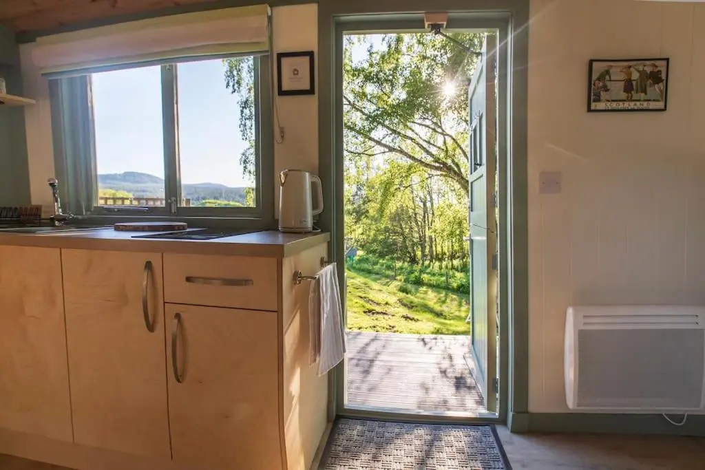 a kitchen with a door leading to a yard at Cosy Shepherds Hut with hot tub in the Scottish Highlands in Stittenham