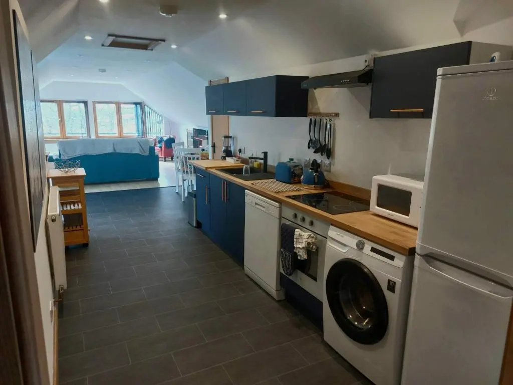 a kitchen with blue cabinets and a washer and dryer at Kiledinmuir in Tore