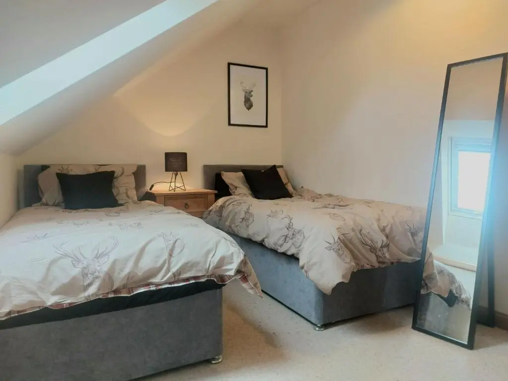 a bedroom with two beds and a mirror at Kiledinmuir in Tore