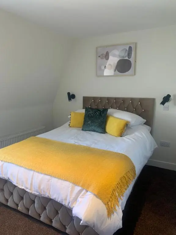 a bedroom with a large bed with yellow pillows at STAG & THISTLE HOTEL AND RESTAURANT in Fraserburgh