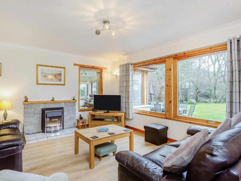a living room with a couch and a fireplace at Balnagowan Mill in Nethy Bridge