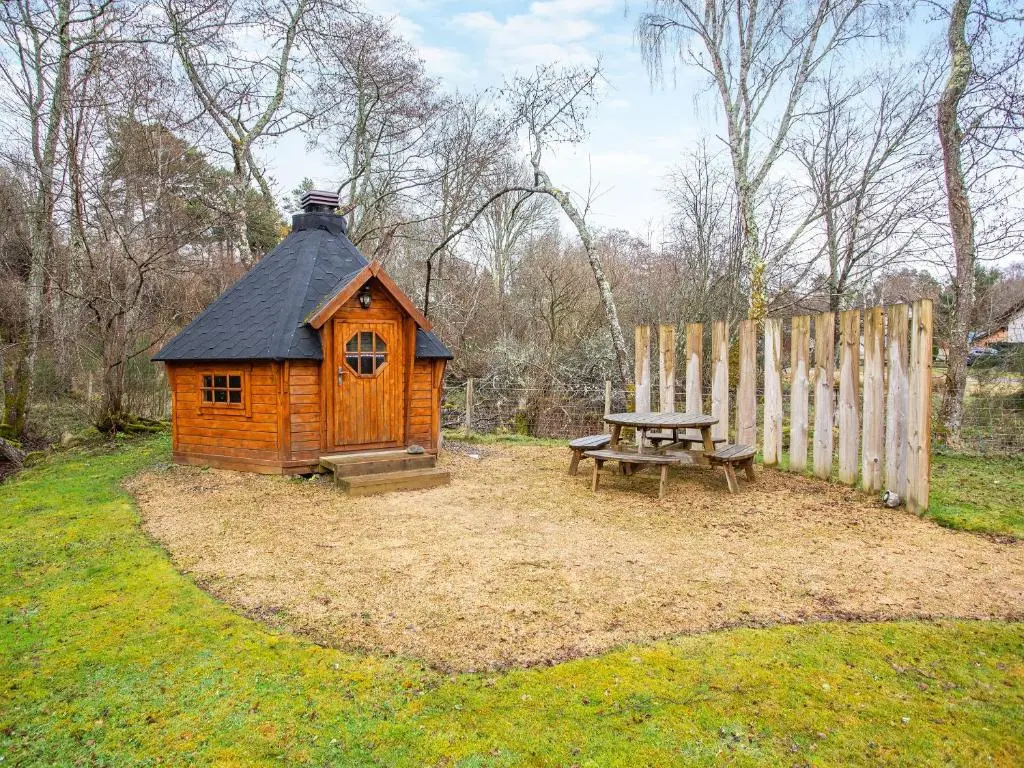 a wooden cabin with a picnic table and a fence at Balnagowan Mill in Nethy Bridge