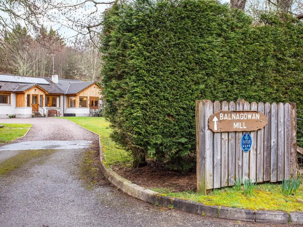 a wooden sign in front of a house at Balnagowan Mill in Nethy Bridge