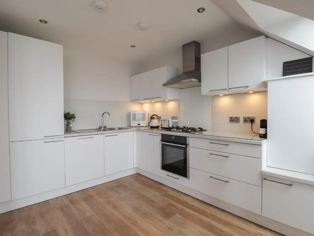a kitchen with white cabinets and a woman in the background at Spinnaker in Lossiemouth