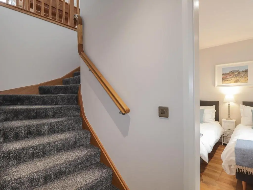a staircase leading up to a bedroom with a bed at Spinnaker in Lossiemouth