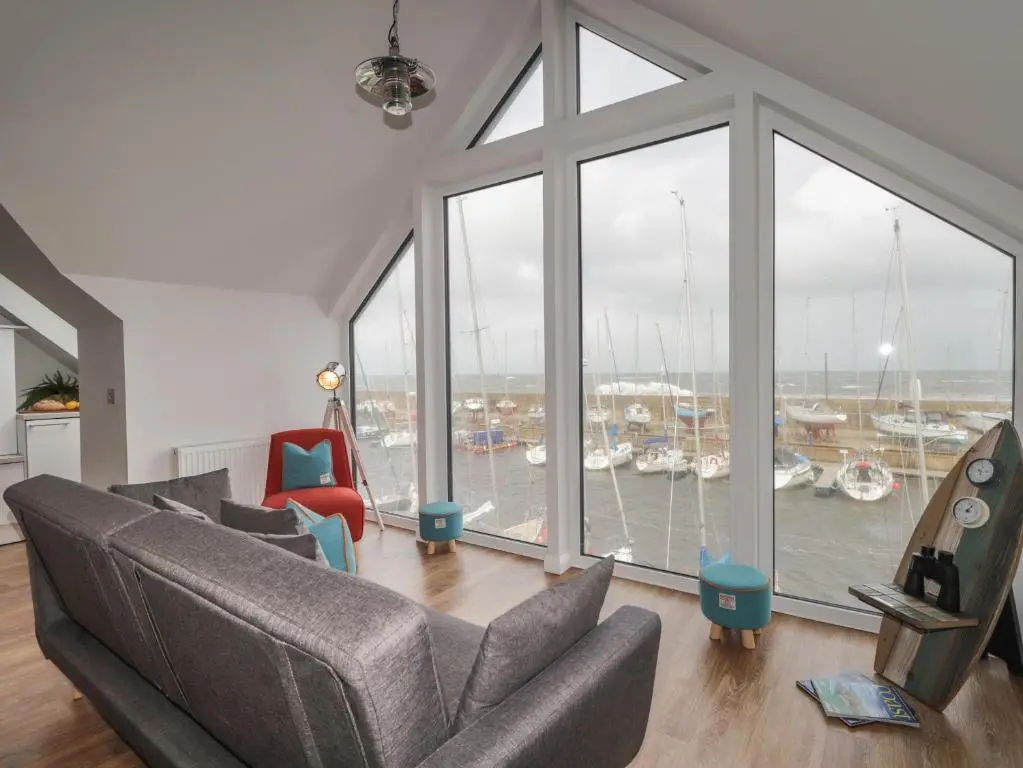 a living room with a large window with boats in the water at Spinnaker in Lossiemouth