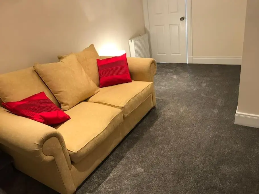 a couch with two red pillows sitting in a room at Heather House, beautiful family home, sleeps 8 in Inverness