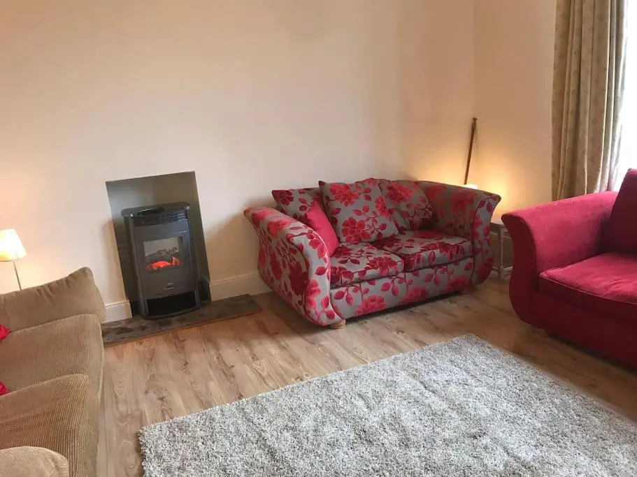 a living room with a red couch and a fireplace at Heather House, beautiful family home, sleeps 8 in Inverness
