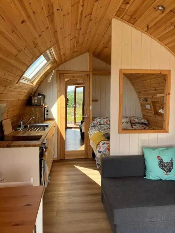 a kitchen and living room with a couch in a tiny house at Migdale Pods Luxury Glamping in Bonar Bridge