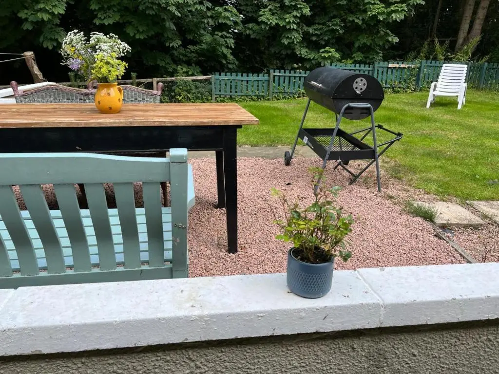 a table and a chair sitting next to a bench at Spacious Cottage in the Grounds of a Scottish Castle in Insch