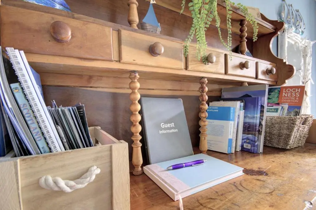 a wooden cabinet with a book and a pen in it at The Apartment at Allt-Sagart in Golspie