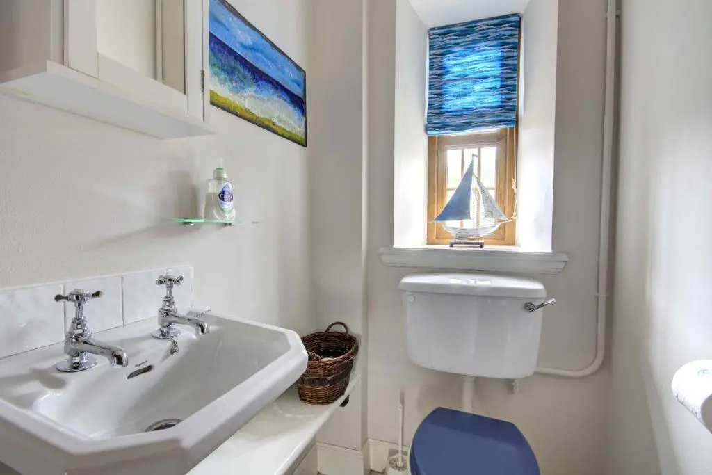 a bathroom with a sink and a toilet and a window at The Apartment at Allt-Sagart in Golspie