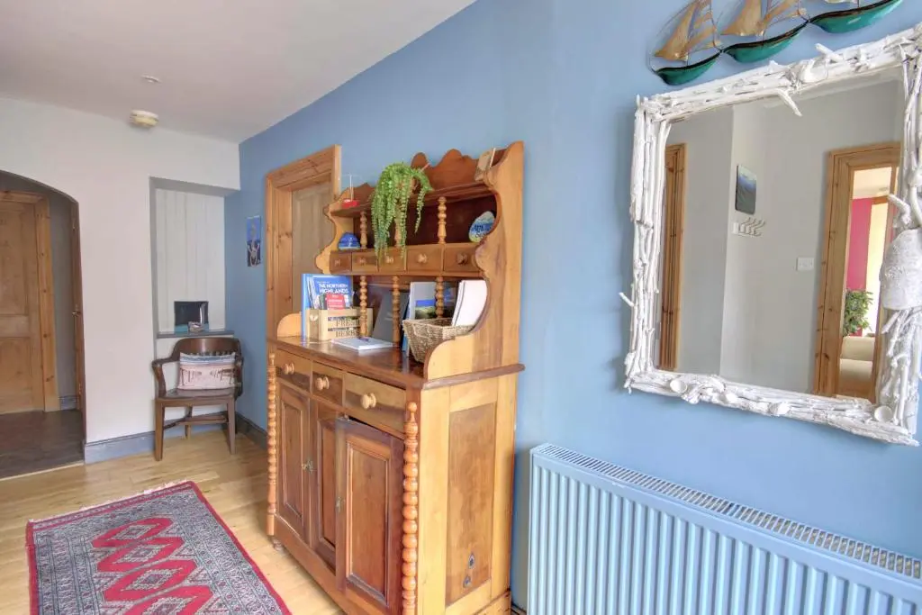 a room with a mirror on a blue wall at The Apartment at Allt-Sagart in Golspie