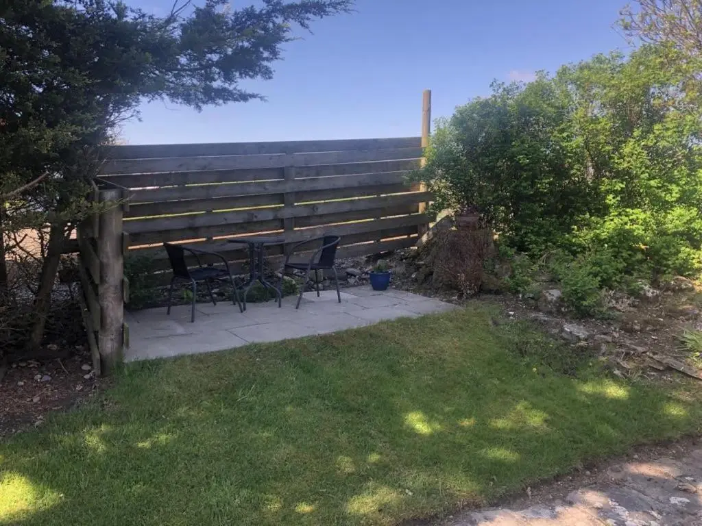a patio with chairs and a table in front of a fence at Ruthven House Holiday Cottages in Kingussie