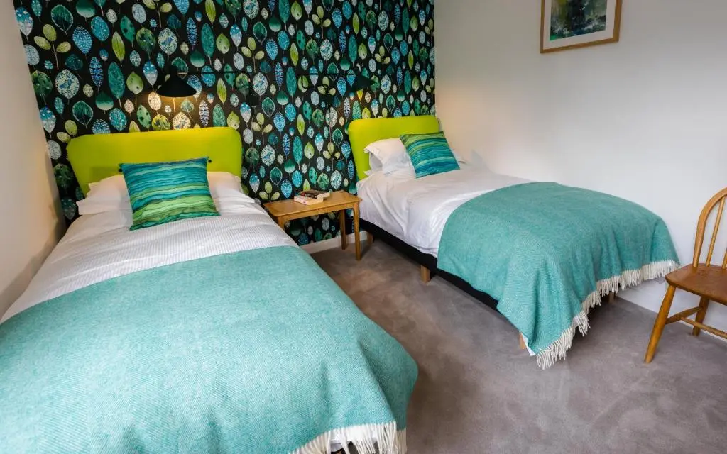 a bedroom with two beds and a wall with a pattern at Strathy House in Aviemore