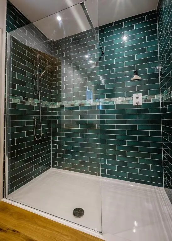 a bathroom with a shower with blue tiles at Strathy House in Aviemore