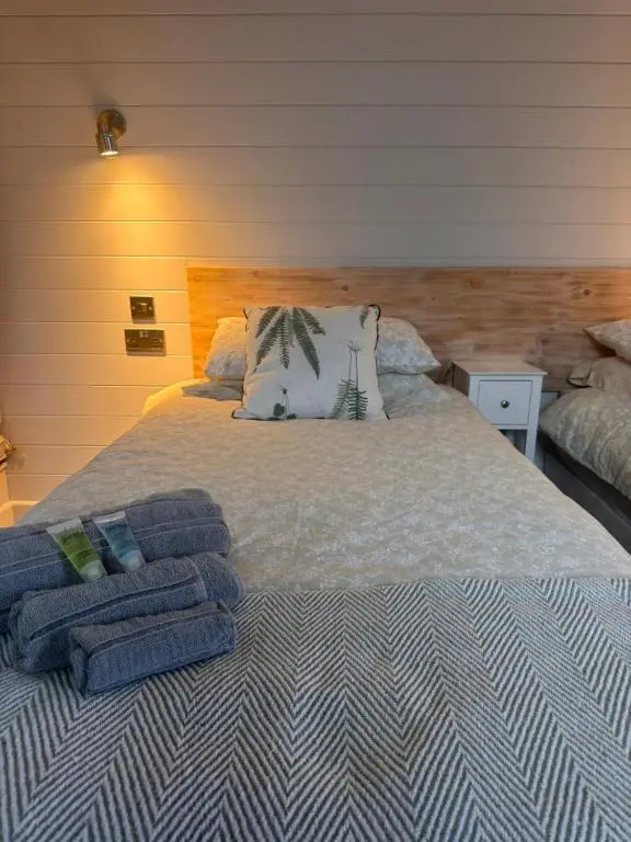 a bed with folded towels on top of it at Bromach Lodge in Latheron
