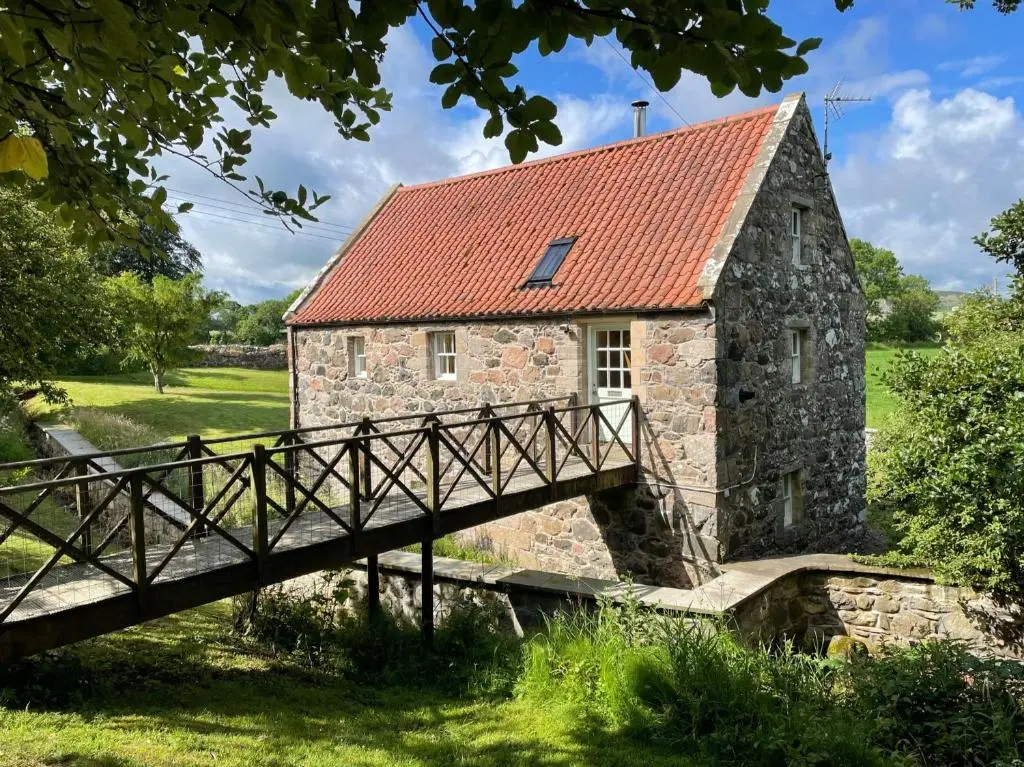 an old stone building with a red roof and a bridge at Stunning Rural Mill House nr beach and harbour in Banff
